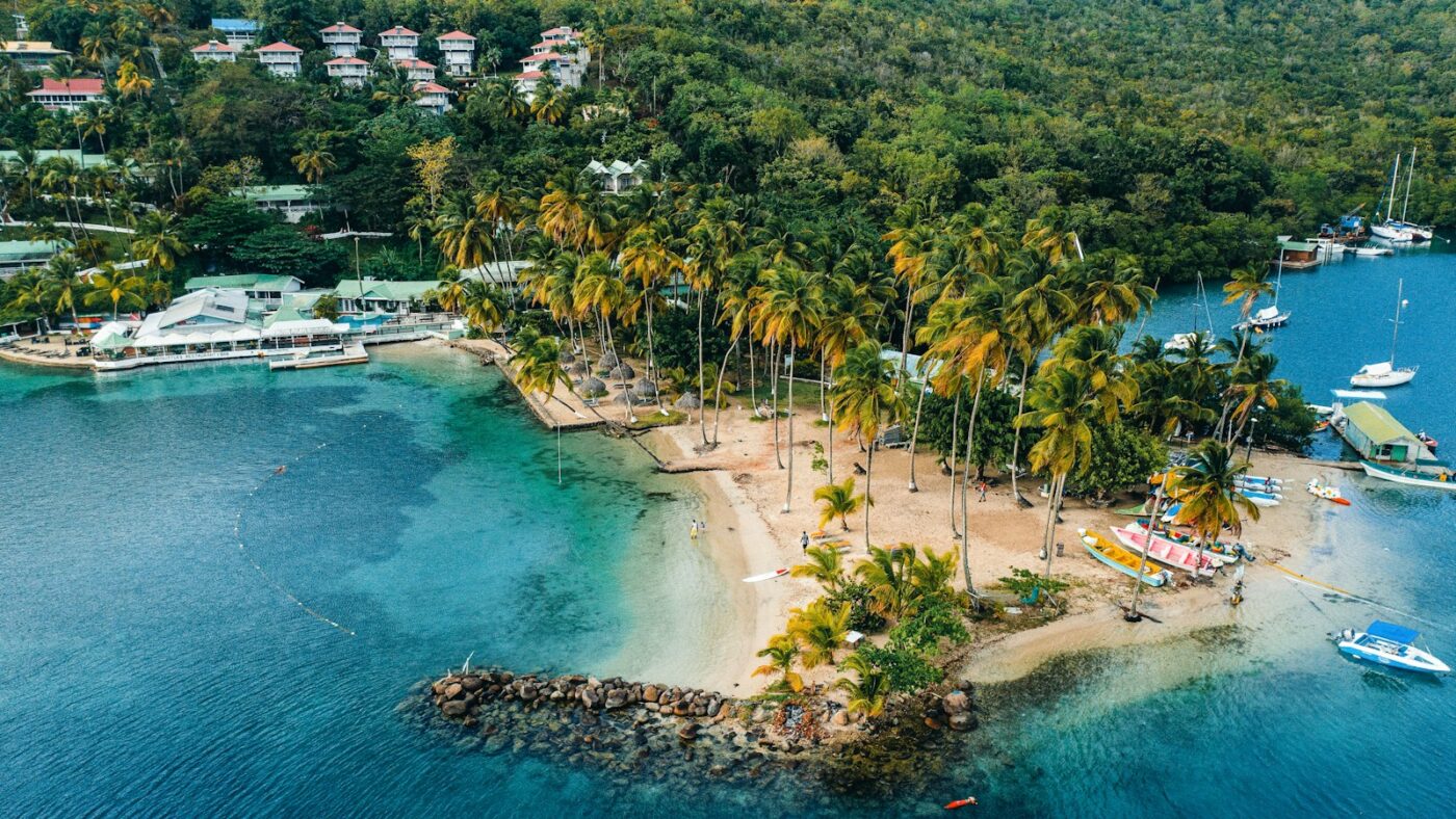 Vista aérea de una isla del Caribe con playa y arrecife, idea para viajar al Caribe