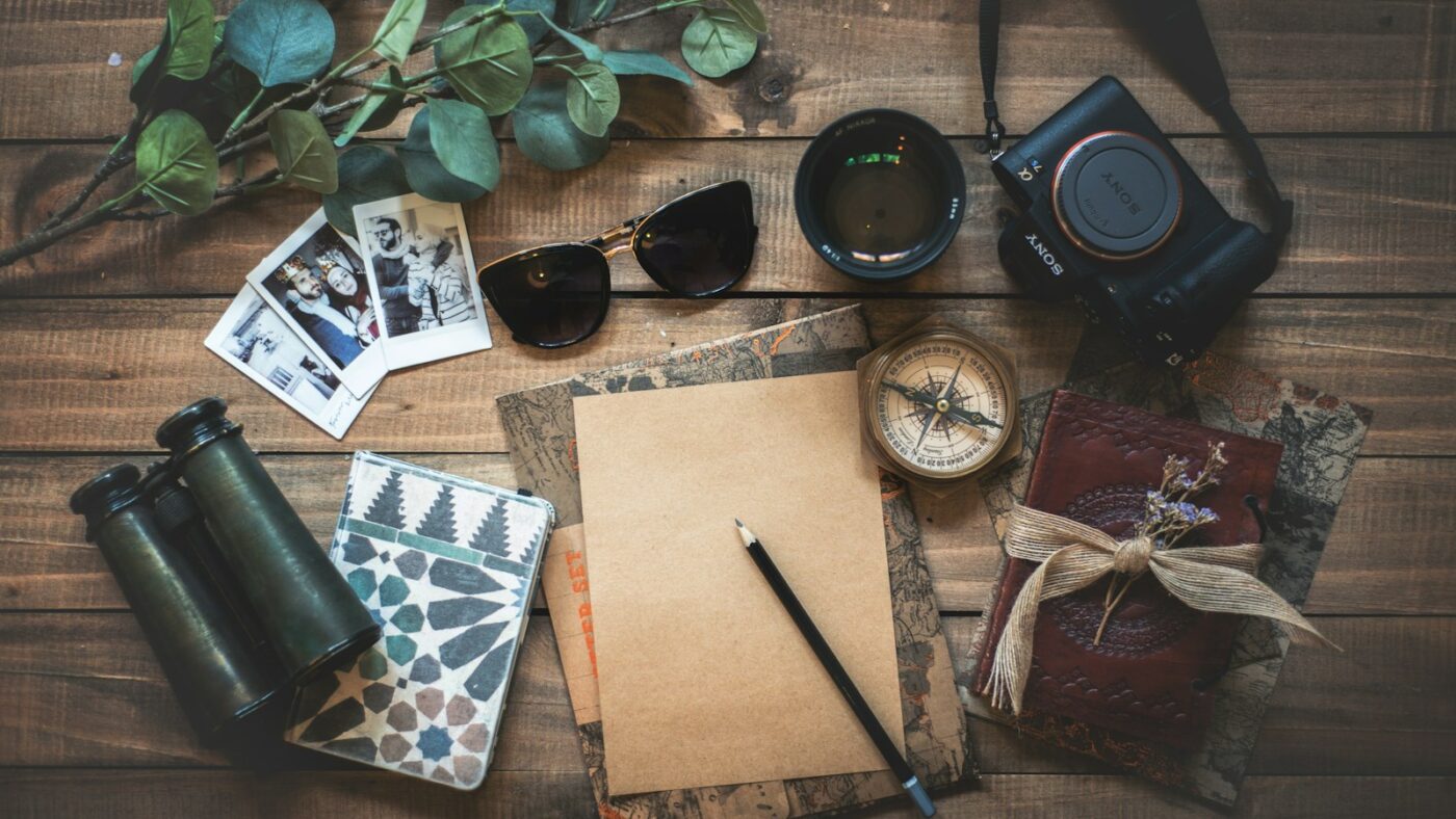 Cuaderno de viaje, cámara y mapas sobre una mesa de la redacción